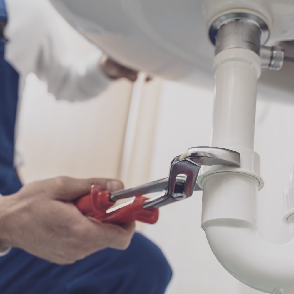 Professional plumber installing or fixing a sink at home